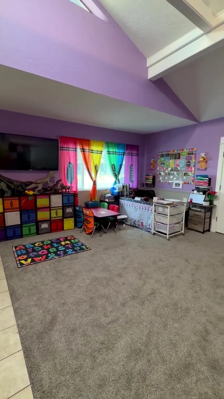 Alphabet rug, rainbow curtains, and color-coded cubbies in the classroom